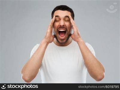 emotions, stress, madness and people concept - crazy shouting man in t-shirt over gray background