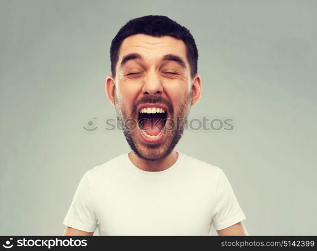 emotions, stress, madness and people concept - crazy shouting man in white t-shirt over gray background (funny cartoon style character with big head). crazy shouting man in t-shirt over gray background
