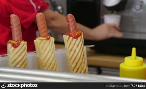 Employee making hot dogs and coffee cup in fast food lunch dinner