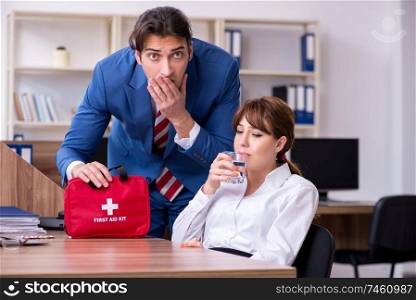 Employee receiving first aid in office. Young employee suffering in the office 