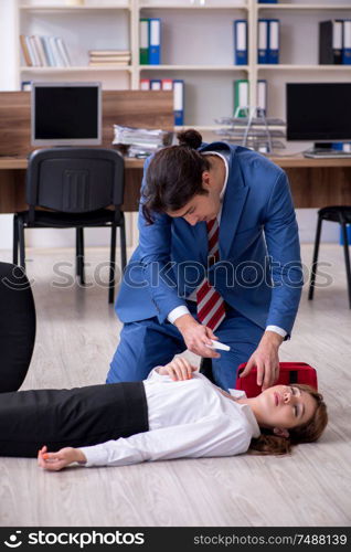 Employee receiving first aid in office. Young employee suffering in the office