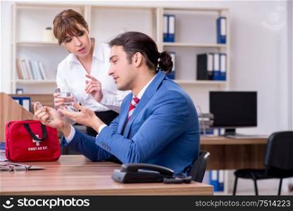 Employee receiving first aid in office. Young employee suffering in the office