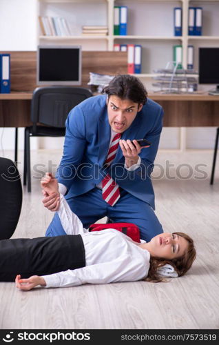 Employee receiving first aid in office. Young employee suffering in the office