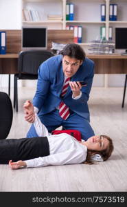 Employee receiving first aid in office. Young employee suffering in the office