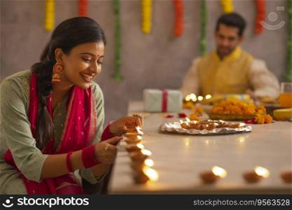 Employees decorating office by placing diyas on table on the occasion of Diwali 