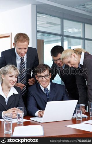 Employees with the boss looking at laptop monitor