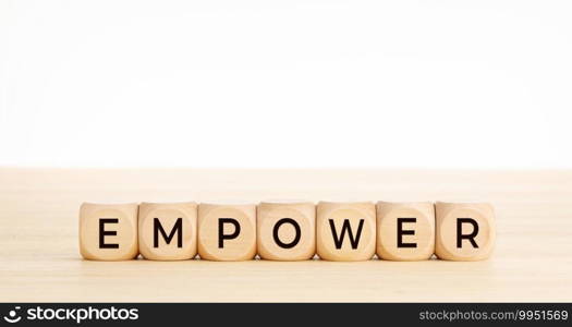 EMPOWER word on wooden blocks on wood table. Copy space. White background