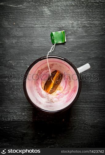 Empty a Cup with a sachet of tea. On a black wooden background.. Empty a Cup