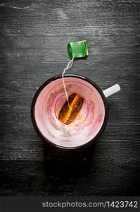 Empty a Cup with a sachet of tea. On a black wooden background.. Empty a Cup