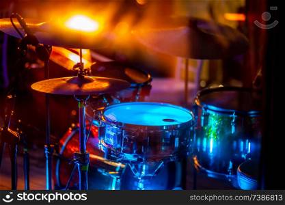 Empty abstract light illuminated stage with drumkit and microphone. Drums in multicolored light during celebrations on stage.
