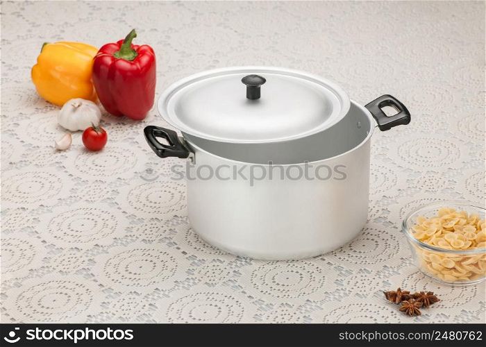 empty aluminum pan on the tablecloth with bell peppers and pasta in glass cup. an empty pan with vegetables