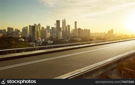 Empty asphalt flyover road with modern cityscape skyline , sunrise scene .