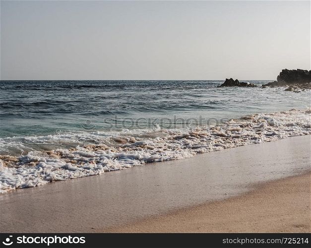 Empty beach against the clear sky and sea waves. Oman, Salalah. Concept of leisure and travel. Empty beach, clear sky and sea waves