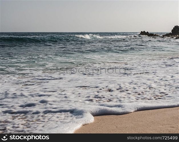 Empty beach against the clear sky and sea waves. Oman, Salalah. Concept of leisure and travel. Empty beach, clear sky and sea waves