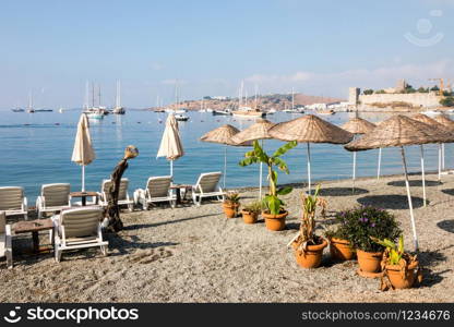 Empty beach in the early morning with boats and castle in the background, Bodrum, Turkey