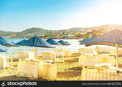 Empty beach loungers without people in quarantine of pandemic, start or the end of summer vacation season . Umbrella on a sunbed near the sea and ocean on vacation with travel and tourism. Hotel, touristic, travel, resort concept. Empty summer beach loungers without people on seaside