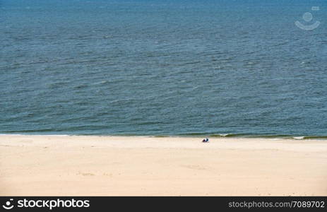 Empty beach scene on the coast at Cape May Point in New Jersey. Single couple on wide beach at Cape May Point in New Jersey