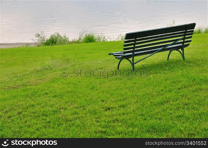 Empty bench on green grass by river