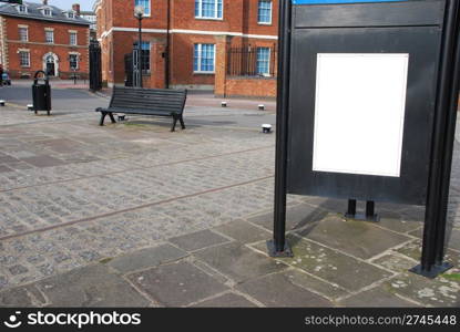 empty billboard at the sidewalk with wooden bench and typical british brick wall buildings