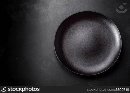 Empty black ceramic plate on a dark concrete background. Preparing the table for a family dinner
