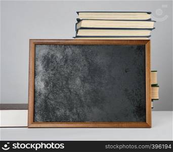 empty black chalk drawing frame and stack of books, gray background