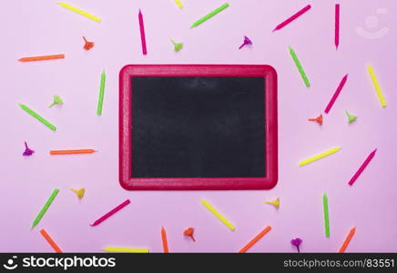 empty black chalk frame on a pink background amidst wax candles for a festive cake