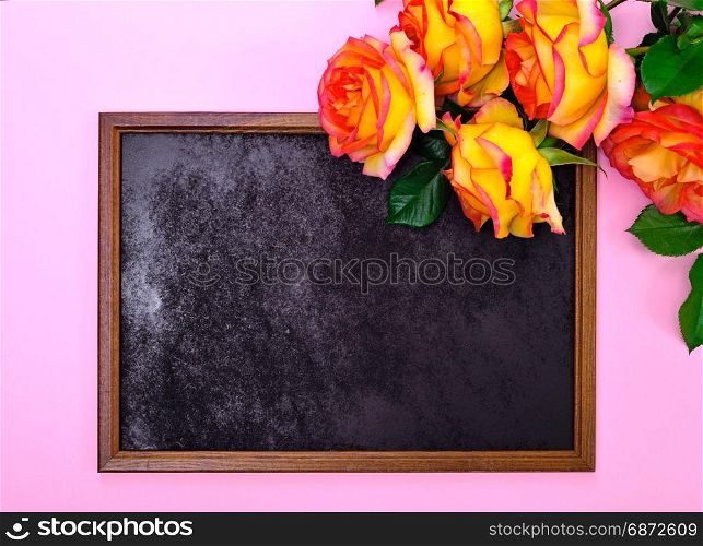 empty black frame and a bouquet of yellow roses on a pink background