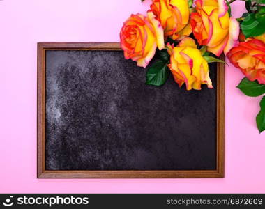 empty black frame and a bouquet of yellow roses on a pink background