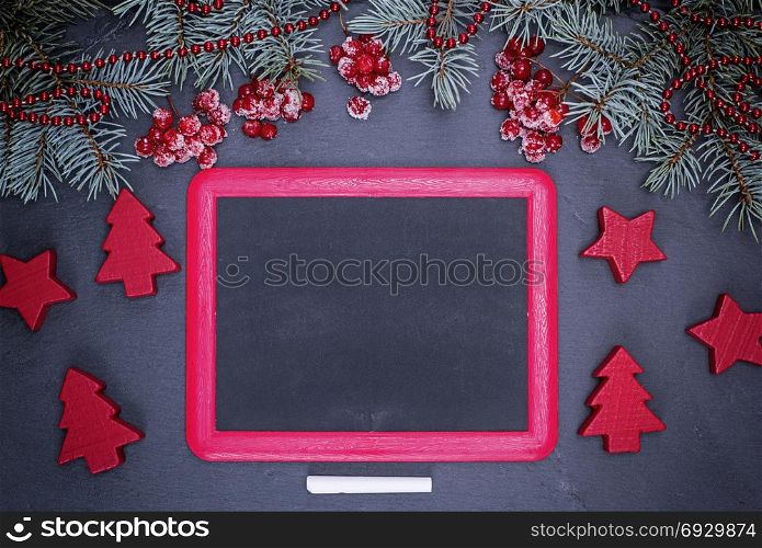 empty black frame and a piece of chalk on a black background, near a festive decoration
