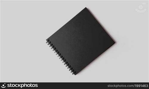 Empty black notebook mockup with soft shadows on neutral grey concrete background.