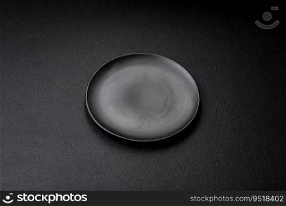Empty black plate over dark sto≠background with©space. Top view