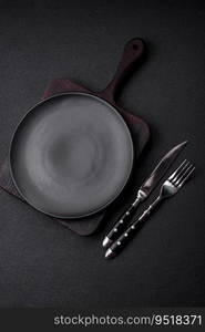 Empty black plate over dark stone background with copy space. Top view