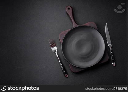 Empty black plate over dark stone background with copy space. Top view