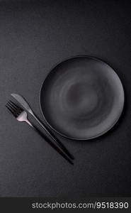 Empty black plate over dark stone background with copy space. Top view