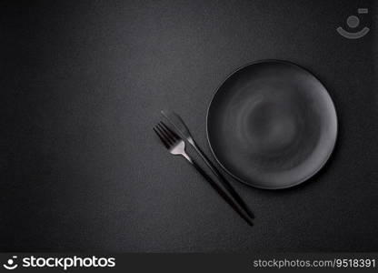 Empty black plate over dark stone background with copy space. Top view