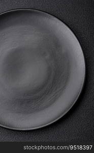 Empty black plate over dark stone background with copy space. Top view