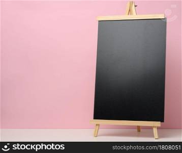empty black slate board on white table, pink background. Place for the inscription of the announcement