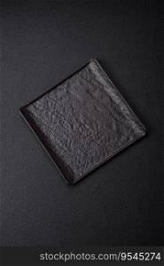 Empty black square ceramic plate on dark concrete background. Cooking Asian food