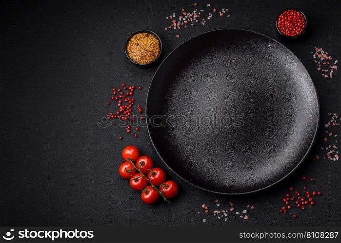 Empty black texture table, cherry tomatoes on a twig, spices, salt and herbs. Ingredients for cooking at home