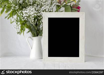 empty blank frame with flower vase white table