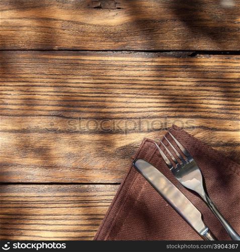 Empty board with fork and knife on wooden table. Top view. Empty board with fork and knife on wooden table