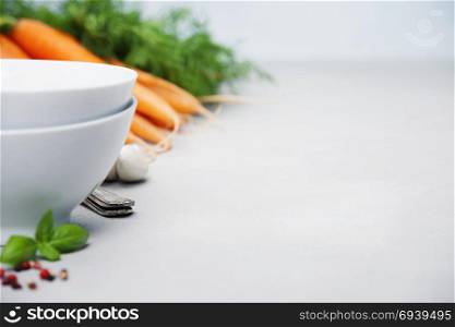 Empty bowls and vegetables on concrete background
