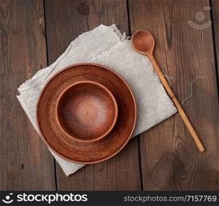 empty brown ceramic plates and wooden spoon on a wooden table, top view