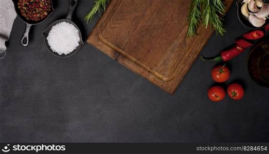Empty brown wooden board and spices on black table, top view