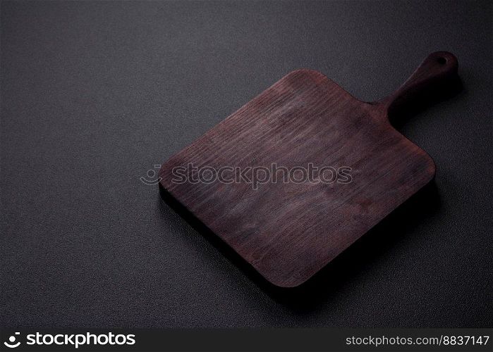  Empty brown wooden cutting board on dark concrete background. Cooking at home