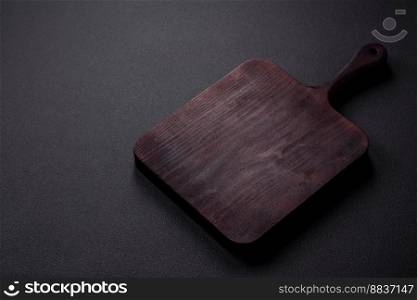 Empty brown wooden cutting board on dark concrete background. Cooking at home