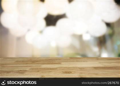 Empty brown wooden table and blur background of abstract of restaurant lights can be used for montage or display your products.