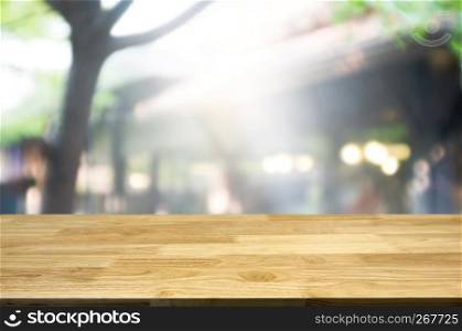 Empty brown wooden table and blur background of abstract of restaurant lights can be used for montage or display your products.