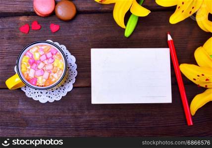 Empty card and red pencil with drink on brown table, top view