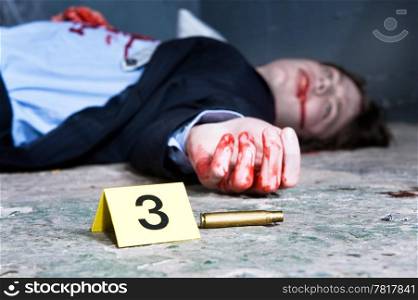 Empty cartridge found on a crime scene with a yellow placard with number three and a dead body in the background